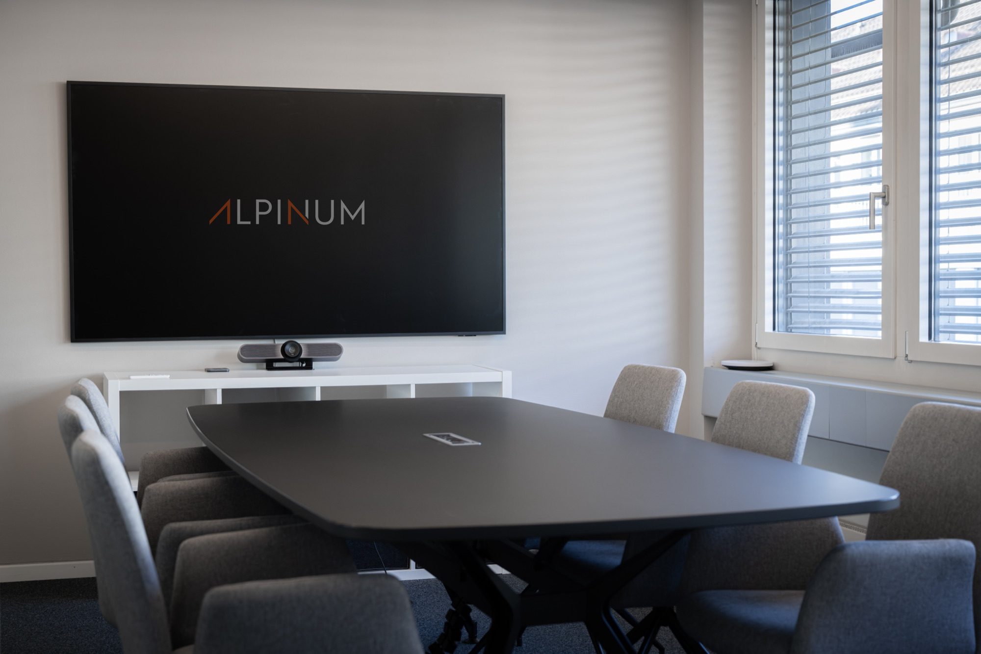 Sitzungszimmer mit grossem Bildschirm und Videokonferenz-Kamera bei ALPINUM